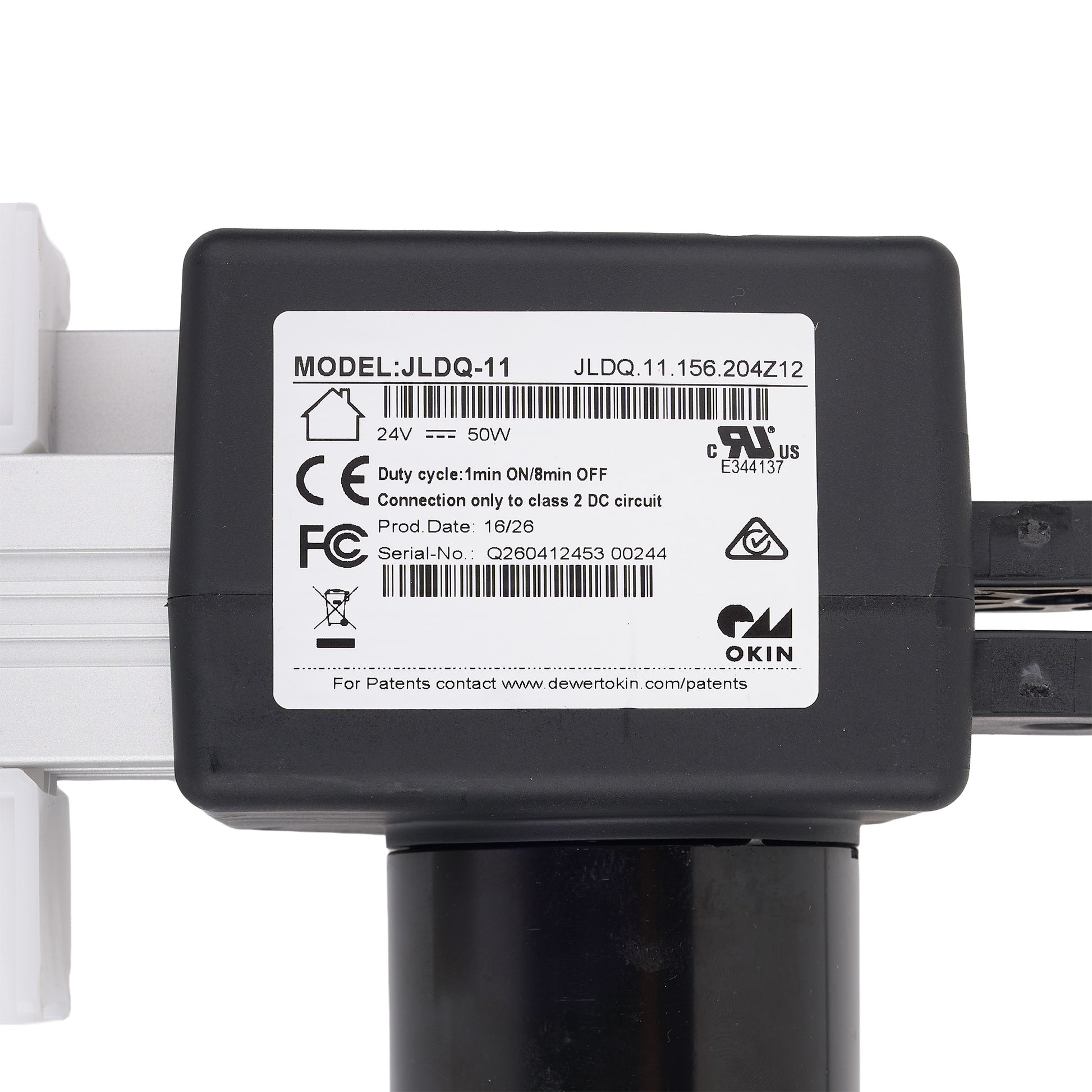 A close-up of a black electronic component with a white label showing model JLDQ-11 and OKIN branding, mounted on a white and black frame against a white background.