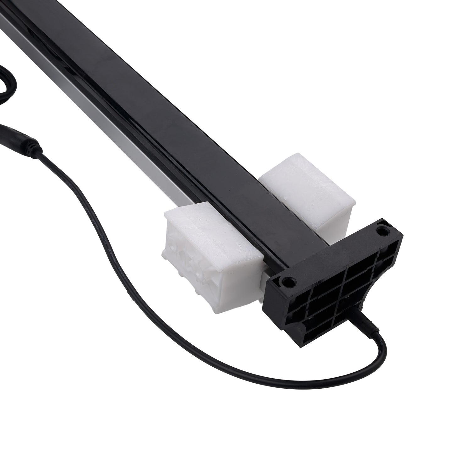 A close-up of a black linear light fixture or LED strip with a black power cable, resting on two white foam blocks against a plain white background.