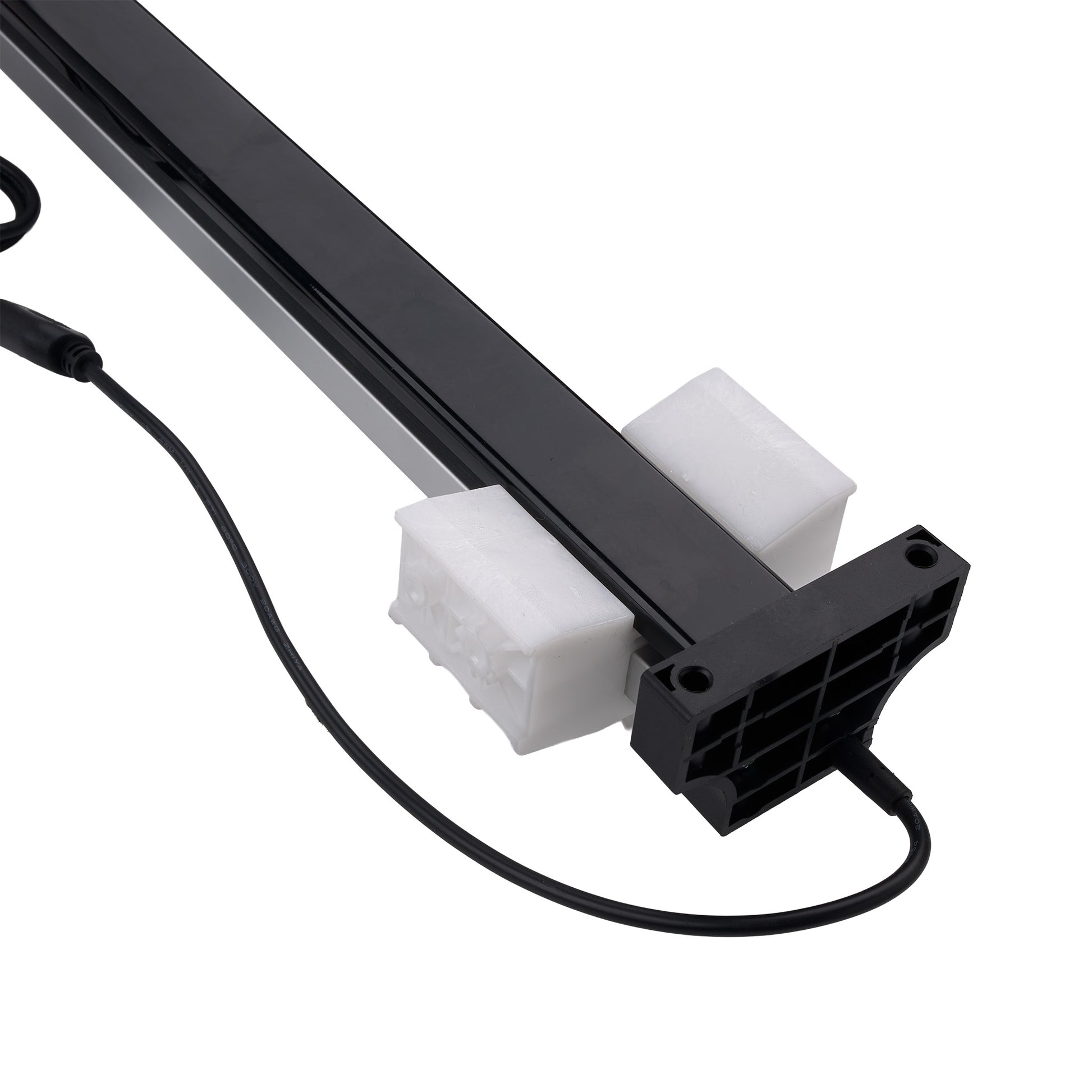 A close-up of a black linear light fixture or LED strip with a black power cable, resting on two white foam blocks against a plain white background.
