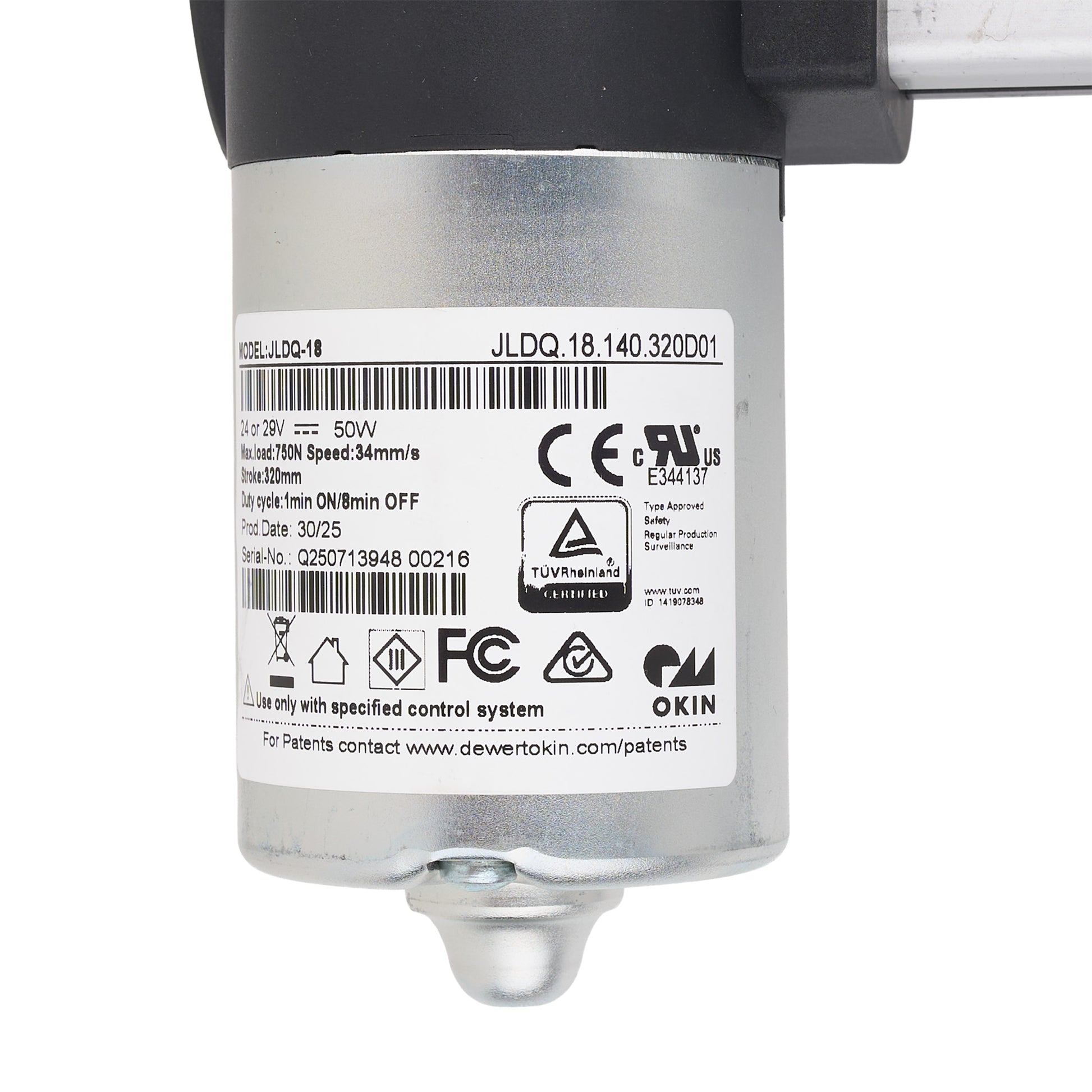 A close-up of a silver cylindrical industrial motor or pump component with a black top section, a white product label showing barcodes and certification marks, and a small metal fitting at the bottom, photographed on a white background.