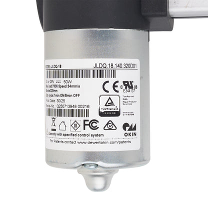 A close-up of a silver cylindrical industrial motor or pump component with a black top section, a white product label showing barcodes and certification marks, and a small metal fitting at the bottom, photographed on a white background.