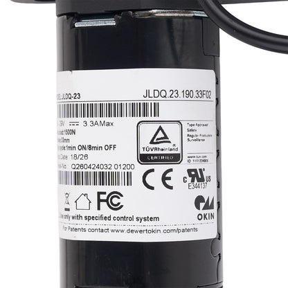 Close-up of a black cylindrical industrial component with a large white label showing barcodes, certification marks including TÜV Rheinland and FCC, and printed text including JLDQ.23.