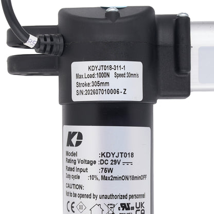 Close-up of a black cylindrical electric pump or motor component with attached cable, top mounting bracket, and two white product labels showing model and technical specifications.