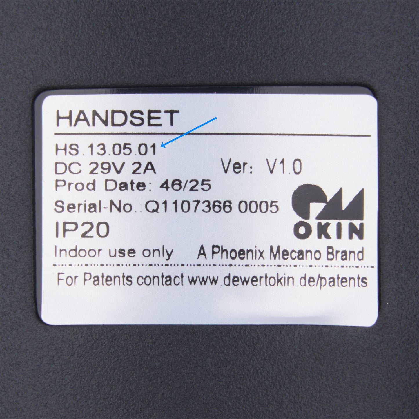 A close-up of a white product label on a dark gray surface, showing text including 'HANDSET', 'OKIN', 'Phoenix Mecano Brand', and 'A PHOENIX MECANO BRAND'.